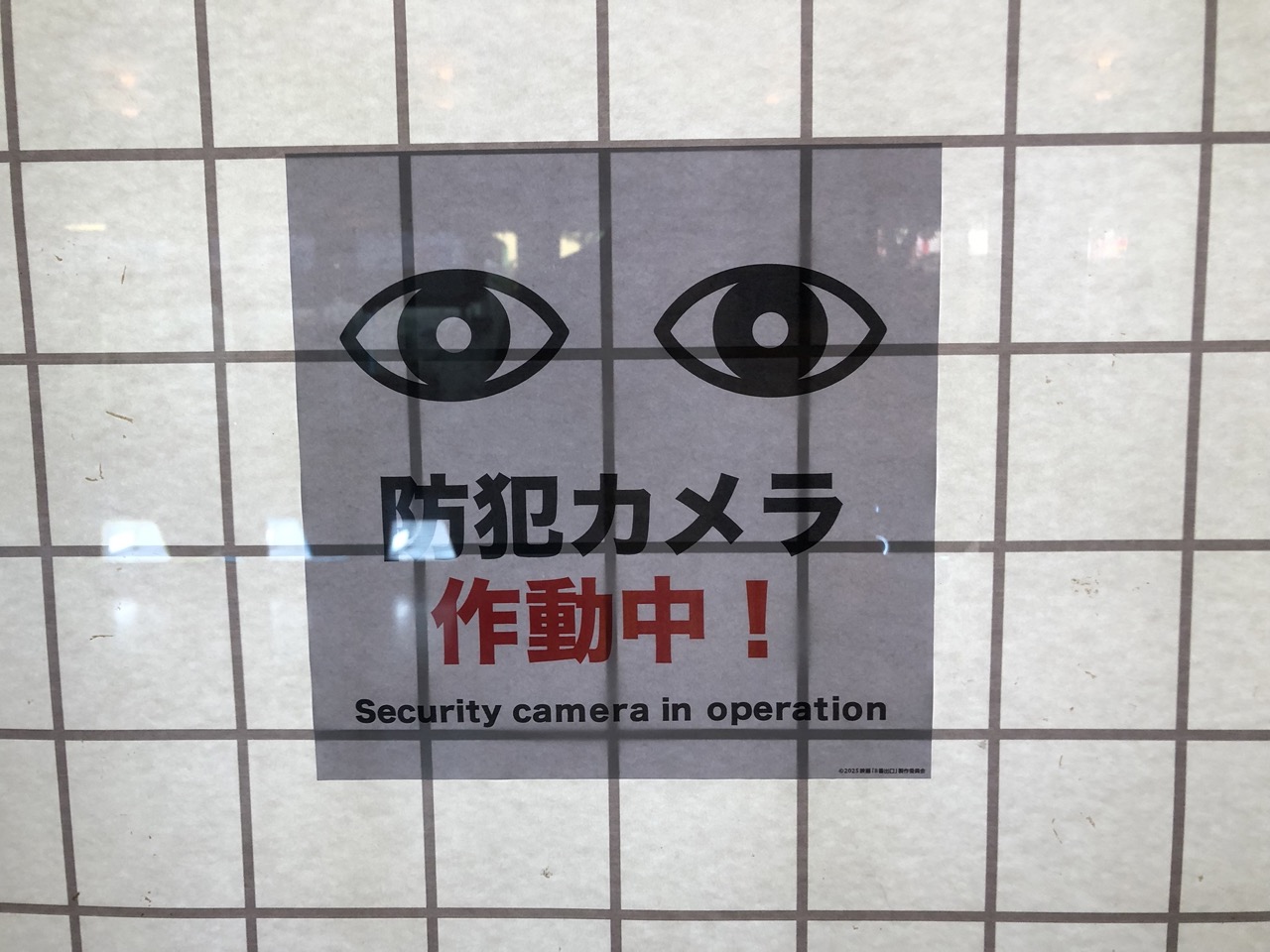 目のマークの張り紙。防犯カメラ作動中と書いてある