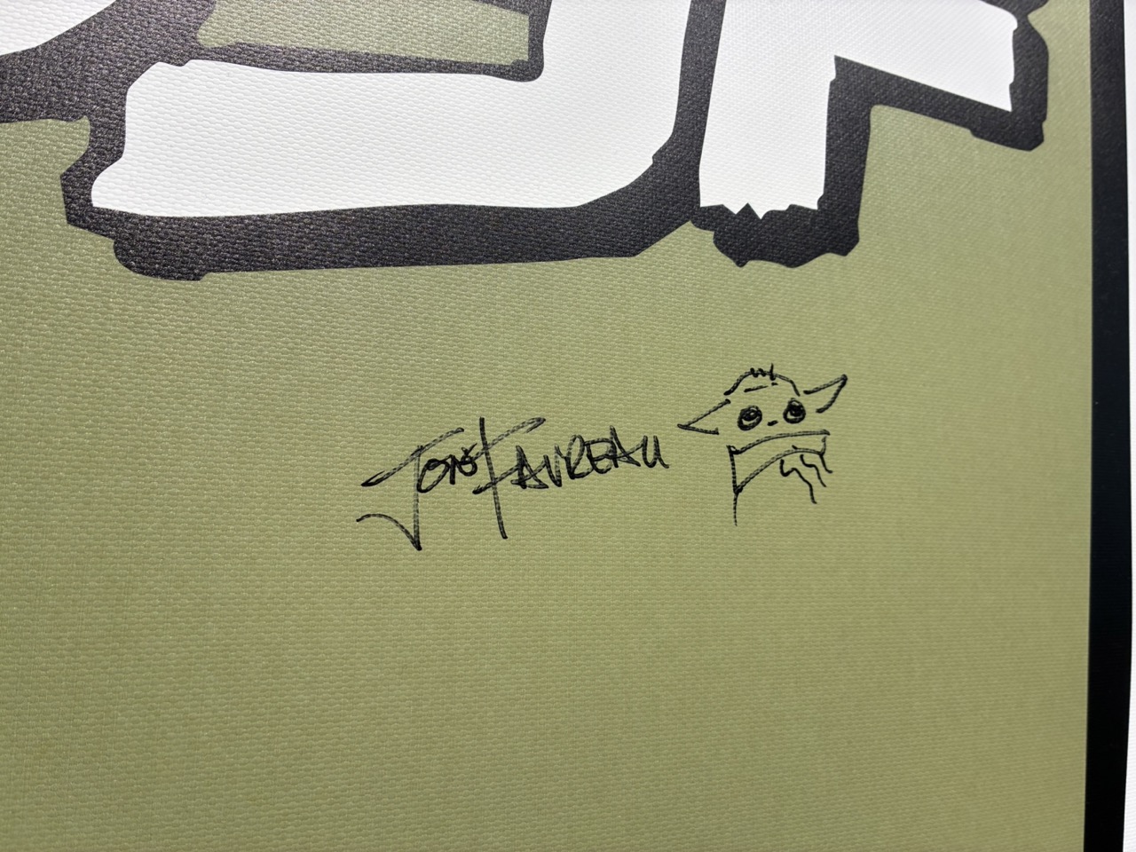 壁に書かれたジョン・ファブローのサインとグローグーのイラスト