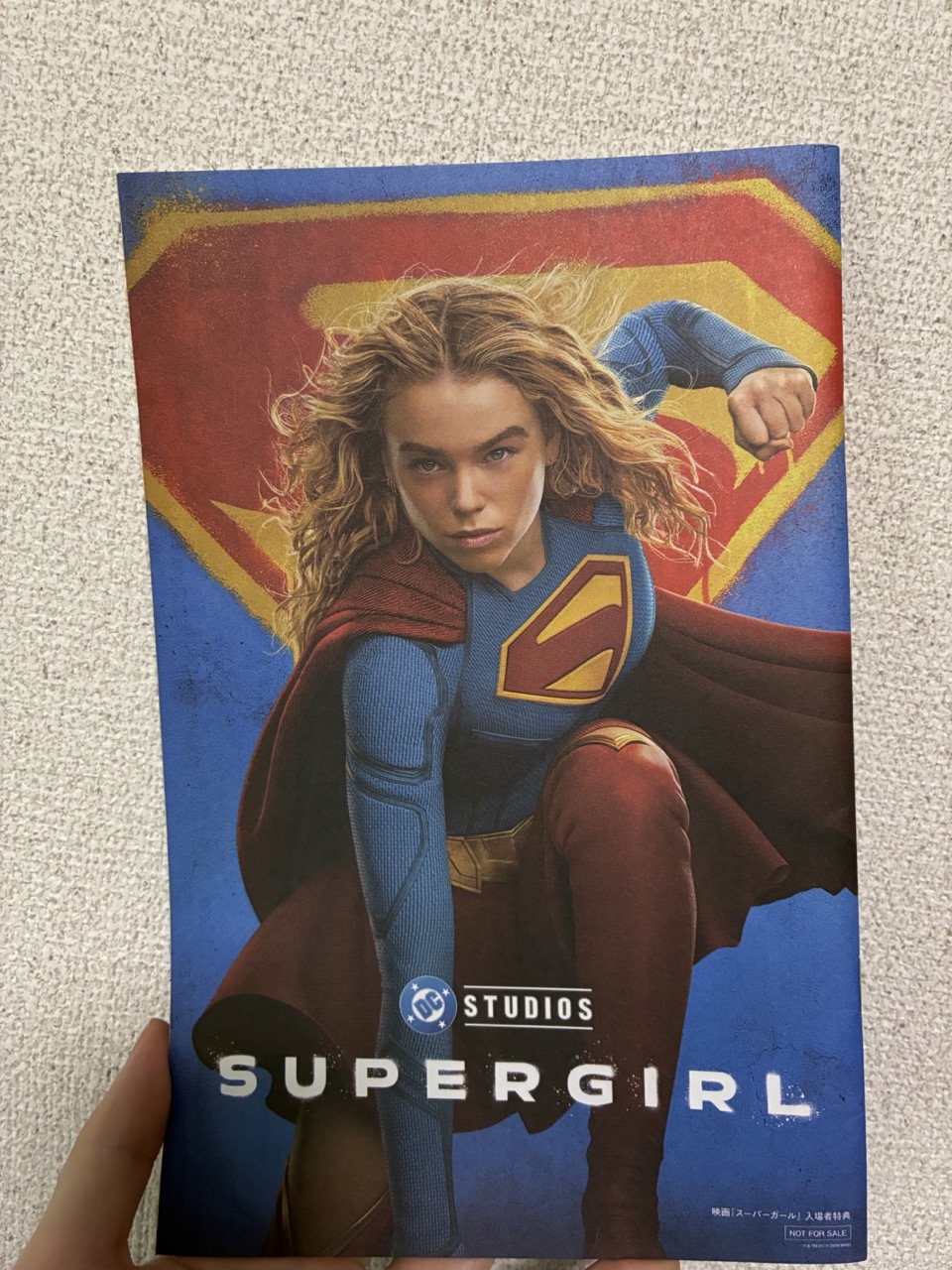 入場特典の裏表紙。スーパーガールが着地ヒーローポーズを取っている映画版のポスターがそのまま印刷されている