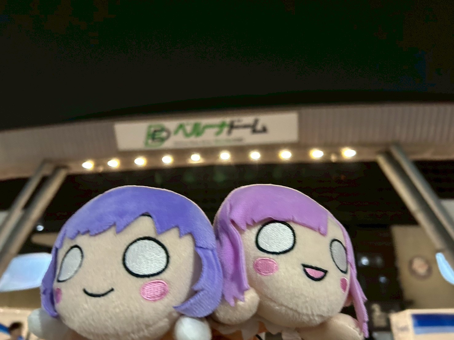 メンバーのぬいぐるみの写真。後ろにベルーナドームの看板